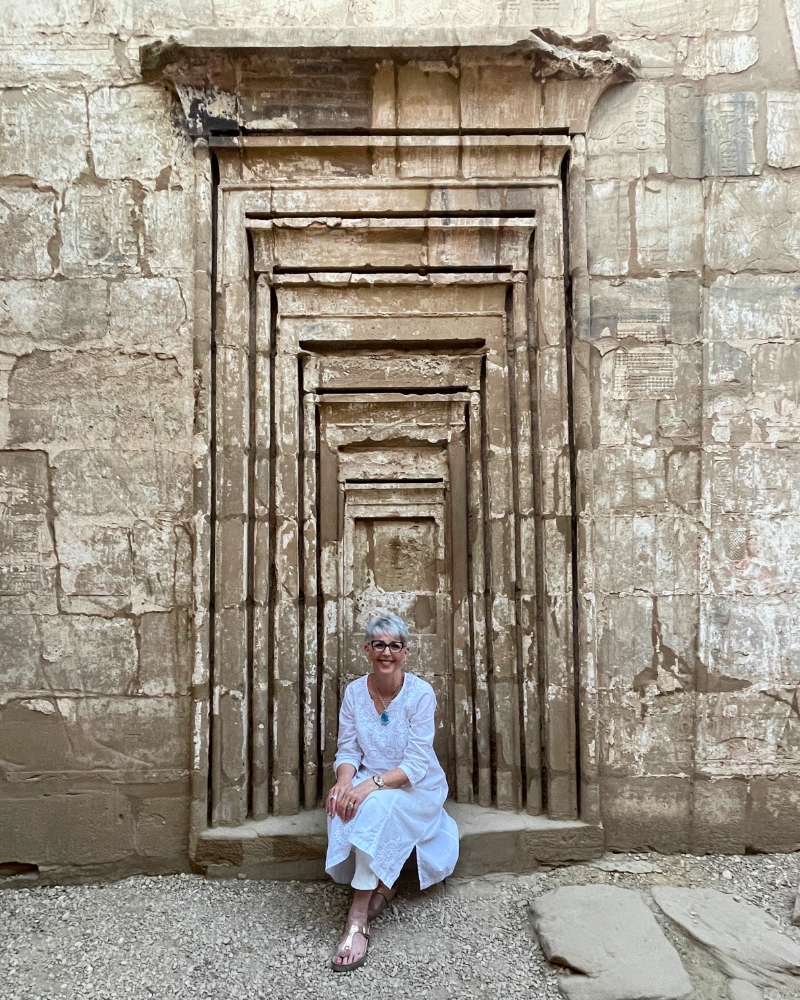 A Personal Transformation: My Egypt Initiation Story Dehyana sitting at a sacred doorway on her Spiritual Tour to Egypt
