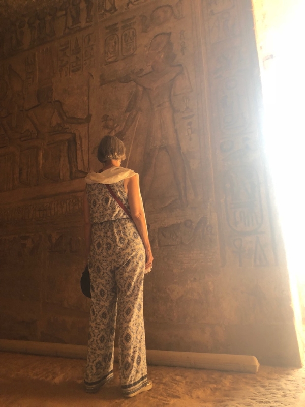 Temples as Energetic Conduits Initiate standing before hieroghlypics as the sun rays pour in through a door -Spiritual awakening in Egypt's sacred temples on our Spiritual Tour to Egypt