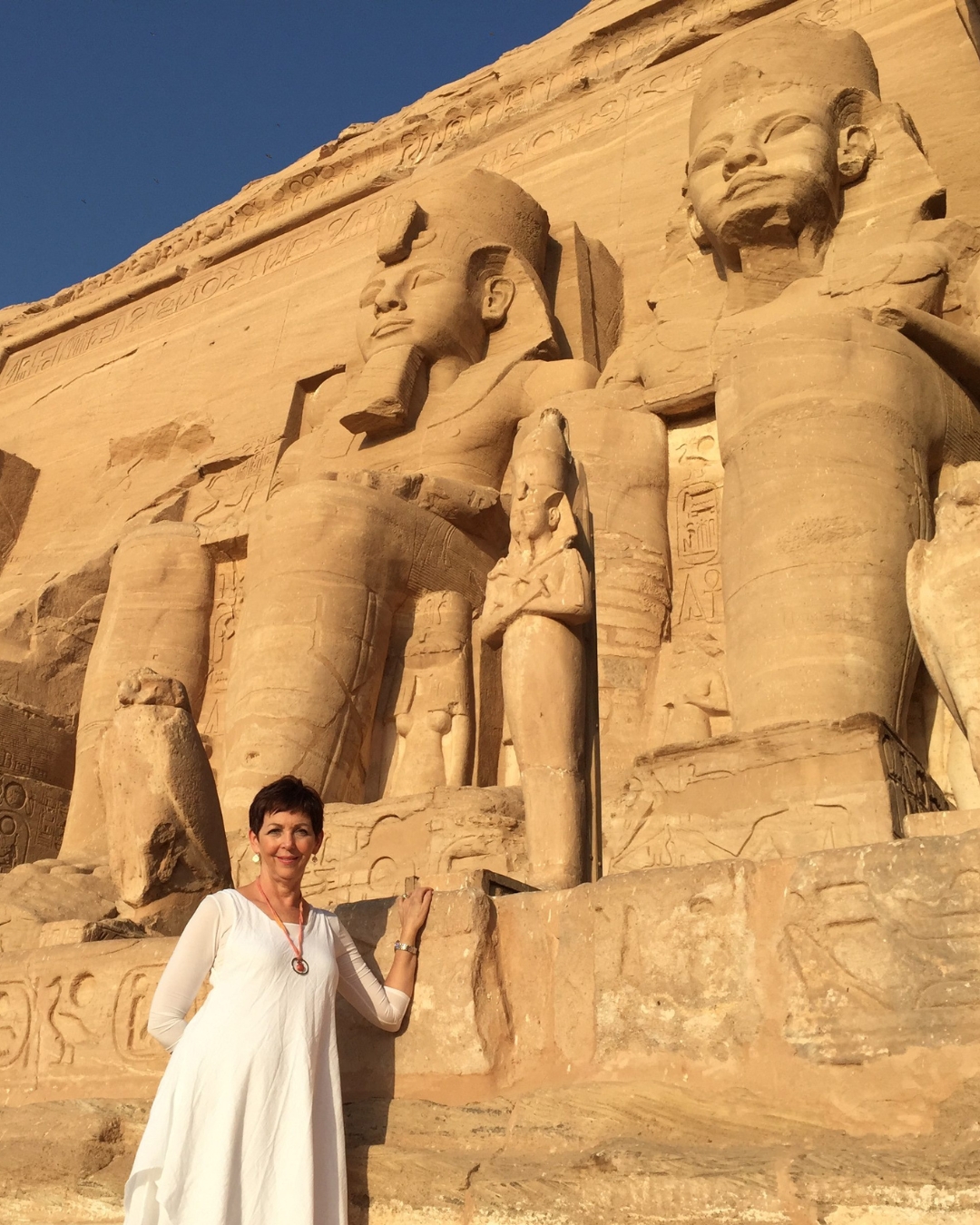 he Sacred Shift of Egypt: Timeless Wisdom for Modern Times Dehyana in front of the colossal statues of Ramses II at Abu Simbel temple front at sunrise- Spiritual awakening in Egypt's sacred temples on our Spiritual Tour to Egypt