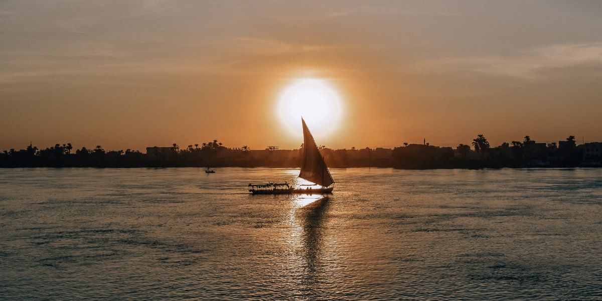 Serene Felucca Ride on the Nile – Heart of Your Egypt Soul Journey Felucca sailing peacefully on the Nile River, symbolizing the serene start of a Spiritual Tour to Egypt and a soul's journey.
