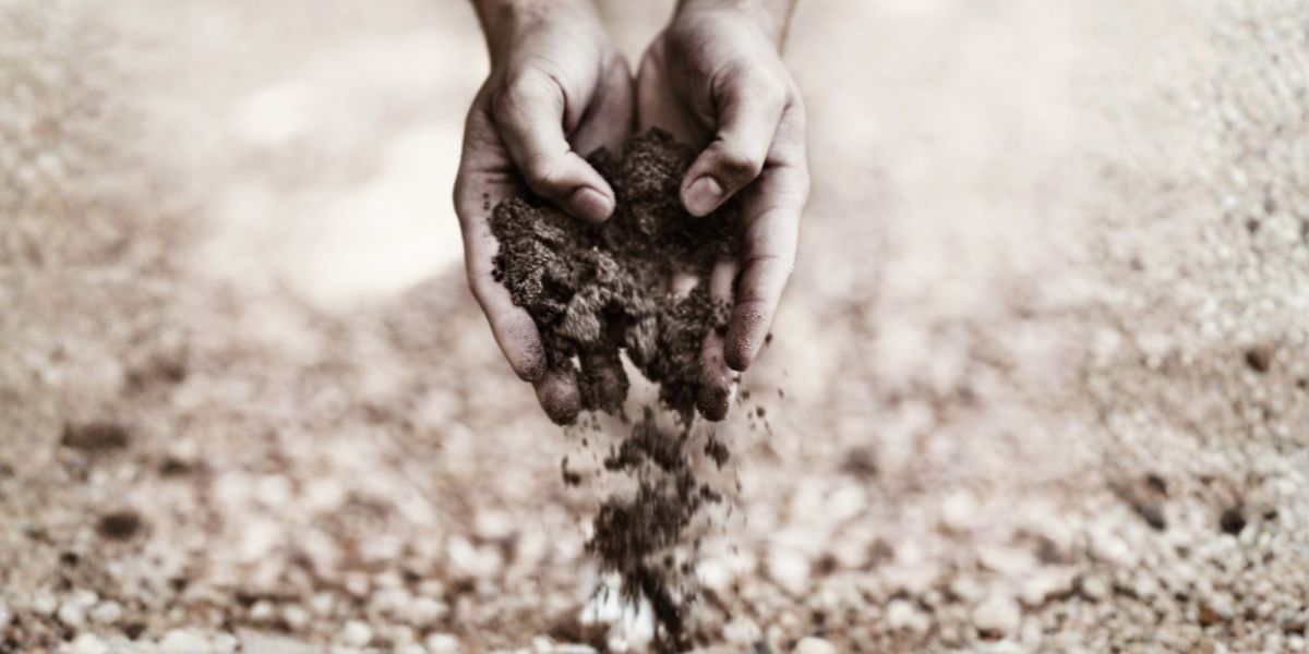 Hands holding soil as earth falls through the fingers