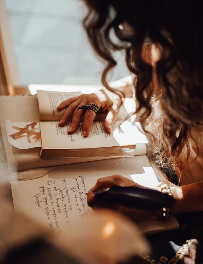 piritual Journaling for Insight and Self-Discovery A woman writing in a journal beside a candlelit, warm-toned setting, symbolising reflection and self-discovery.