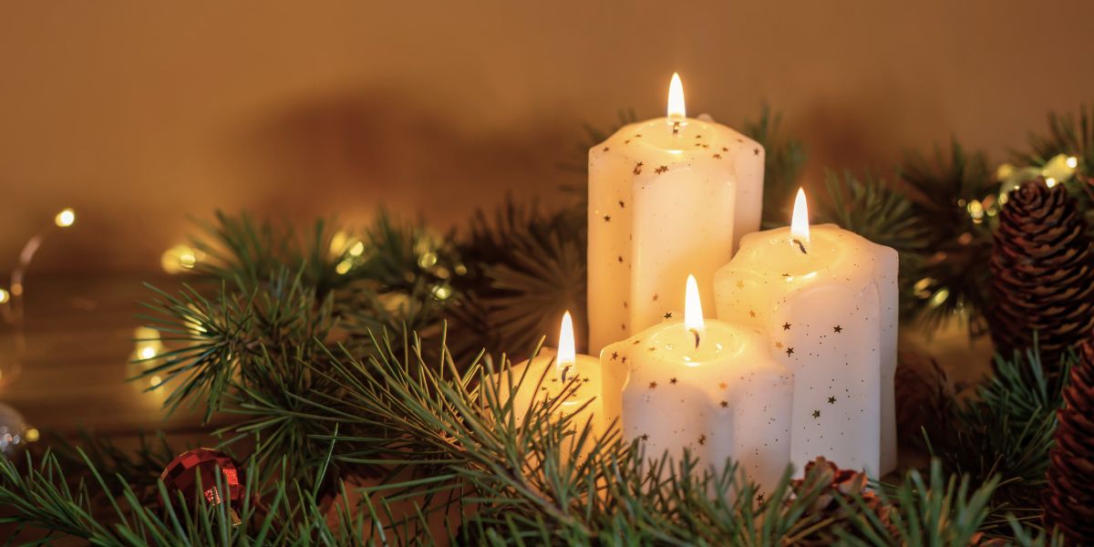 Soft candlelight glowing among winter greenery, symbolising presence and love